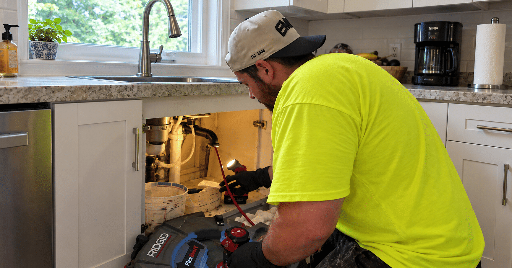 Environmental Plumbing technician cleaning a kitchen sink drain with professional equipment