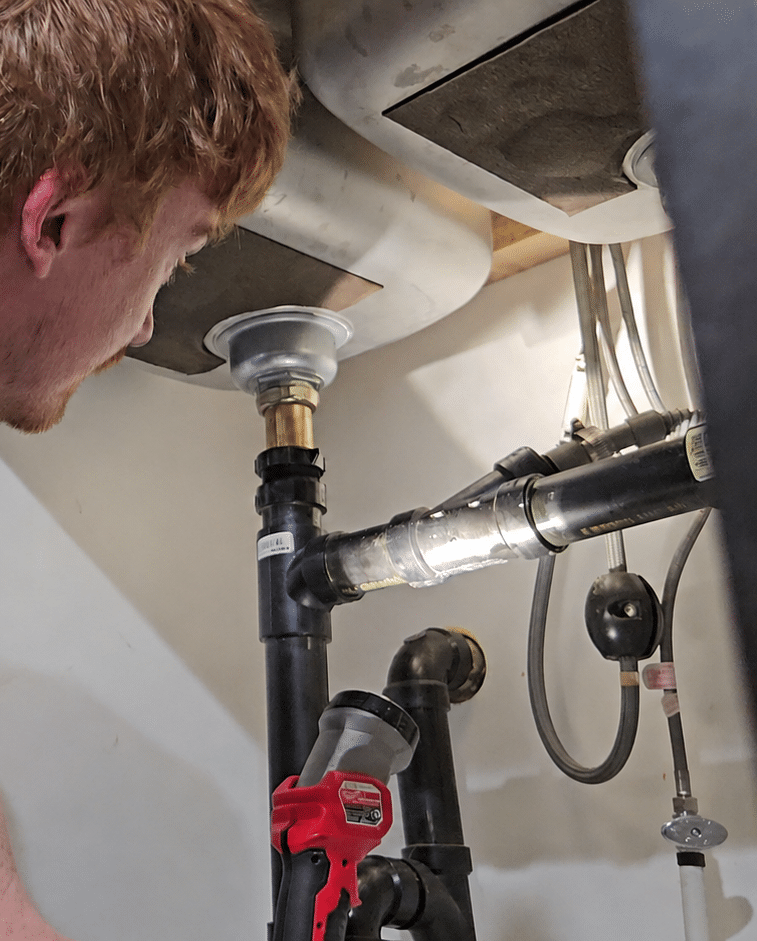 Environmental Plumbing plumber diagnosing a plumbing problem under a sink